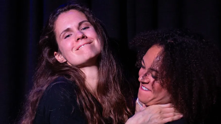 Two women playfully grimacing on stage.