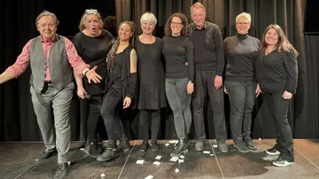 Group of eight people on stage smiling.