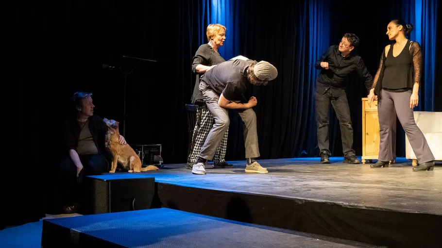 Actors performing on stage with a dog.