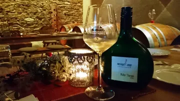 Weinglas und Flasche auf rustikalem Tisch.