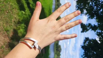 Hand mit Armband, Naturhintergrund.