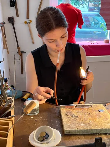 Woman using blowtorch for crafting in workshop.