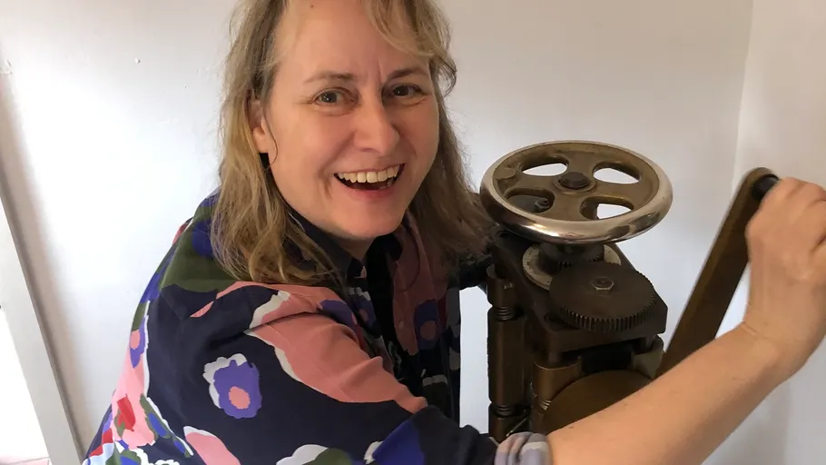 Person lächelt, bedient antike Maschine drinnen.