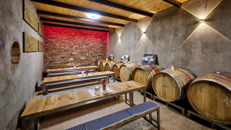 Weinfässer und Bänke im rustikalen Keller.