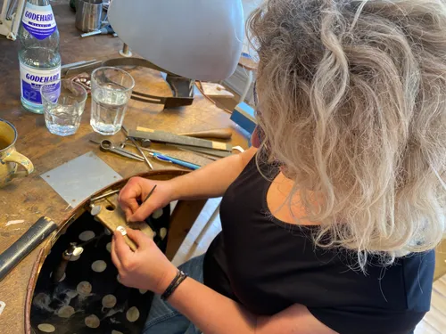 Woman crafting jewelry at a workbench.