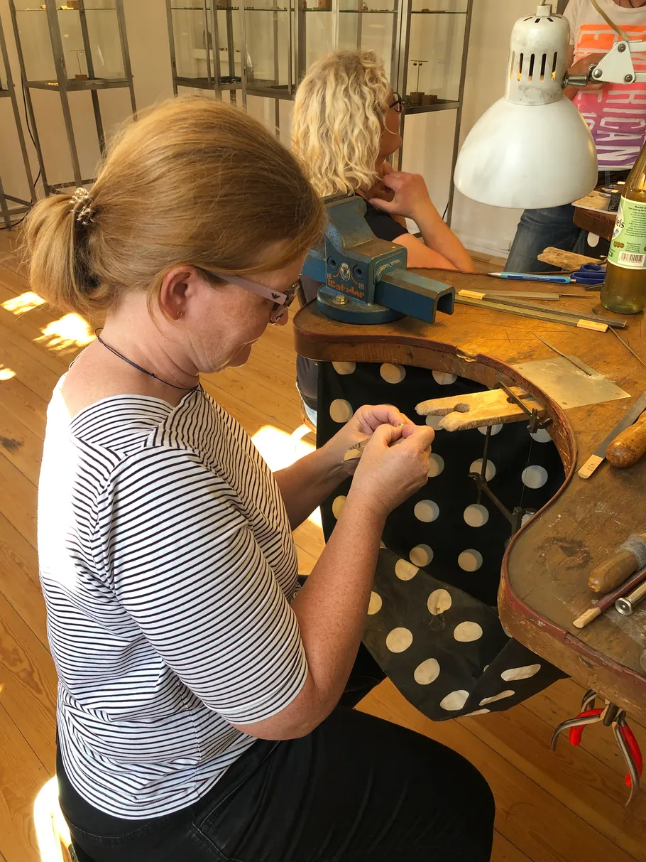 Woman crafting jewelry at workbench.