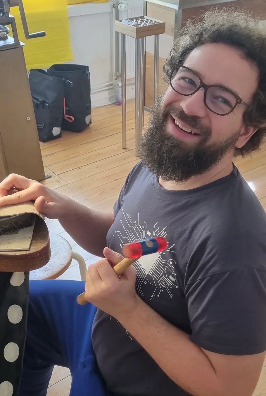 Smiling man holding hammer in workshop.