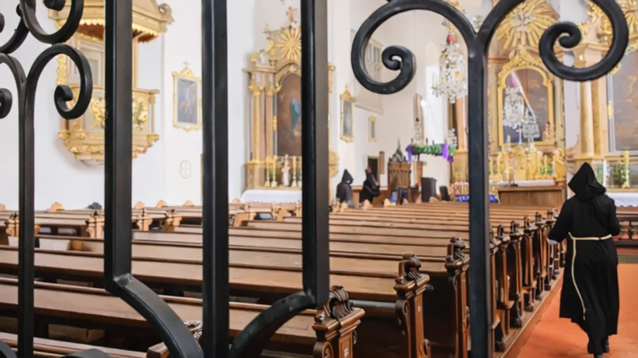 Monks walking inside ornate church interior.