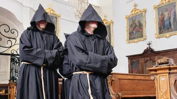 Hooded monks standing in a church.