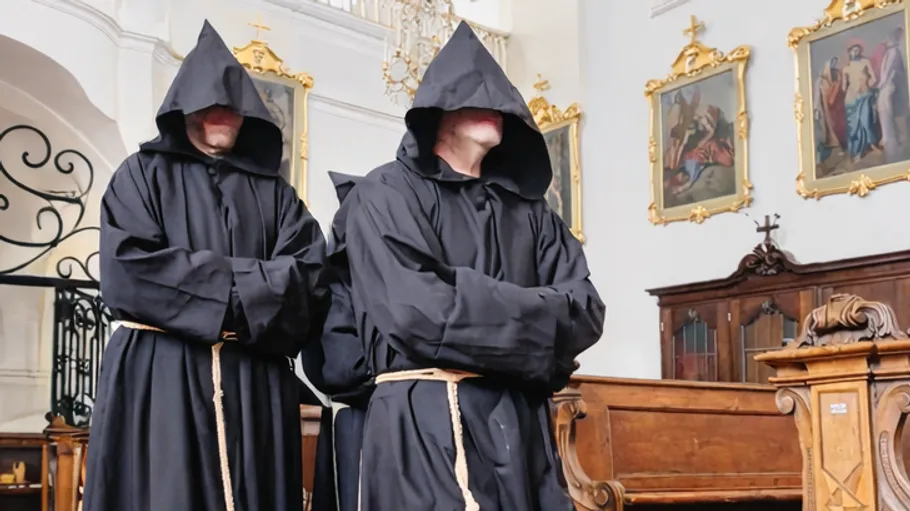 Kapuzentragende Mönche in einer Kirche.