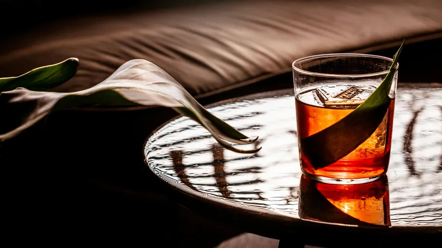 Glass with drink on reflective table surface.