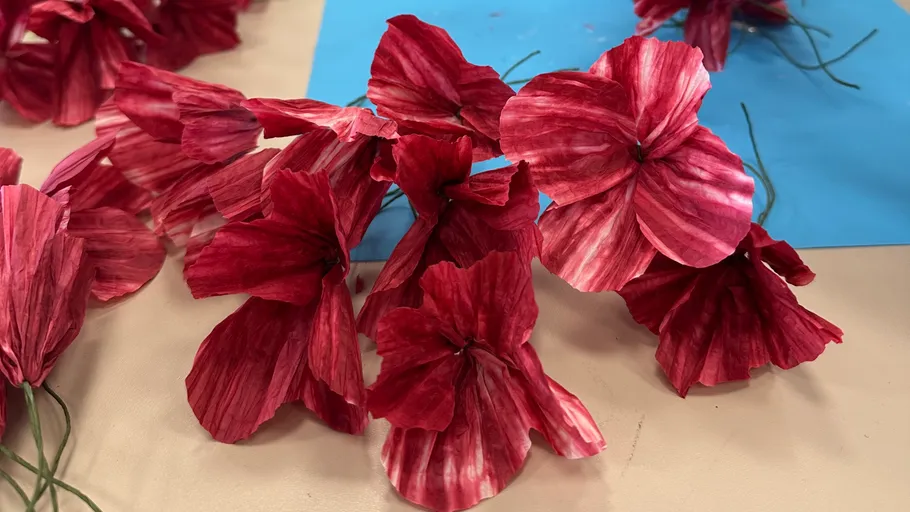 Rote Papierblumen auf blauem Hintergrund.