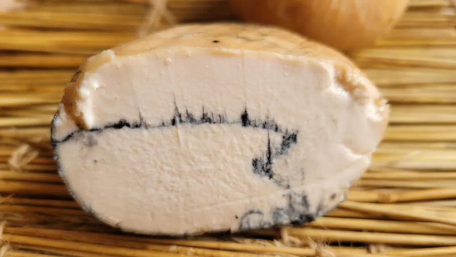 Käse mit schwarzen Streifen auf Strohmatte.