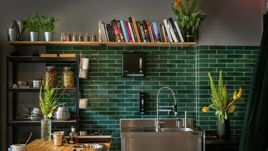 Kitchen with green tiles and modern accessories.