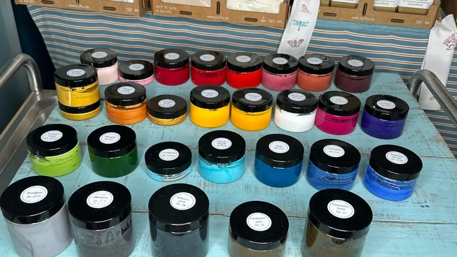 Colorful jars of pigment on a table.