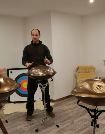 Person spielt Handpan in einem Raum mit Zielscheibe.