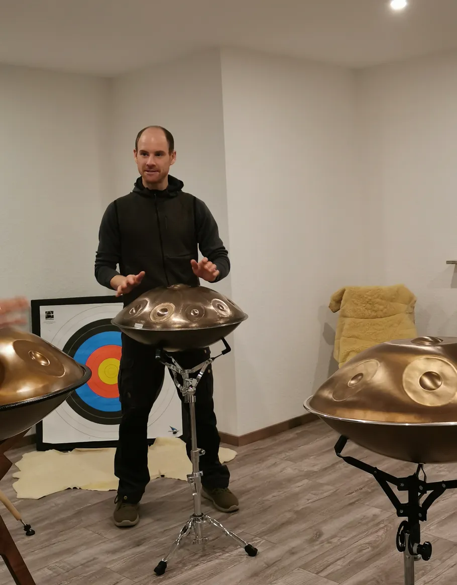 Person playing handpan in a room with archery target.