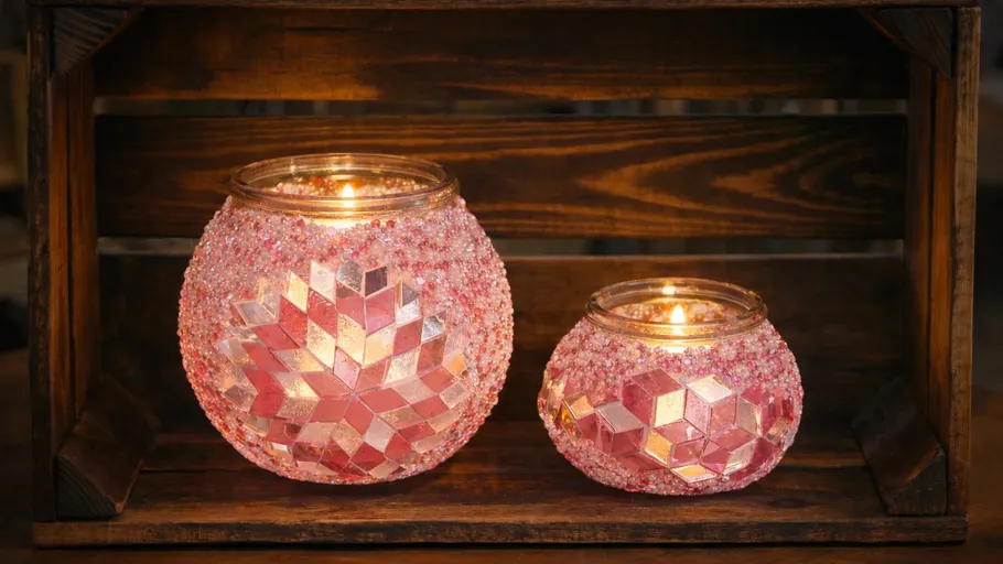 Zwei rosa Mosaikkerzen in Holzkiste.