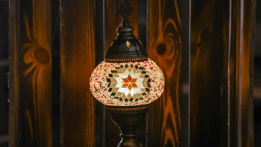 Ornate Glaslampe leuchtend vor Holzhintergrund.