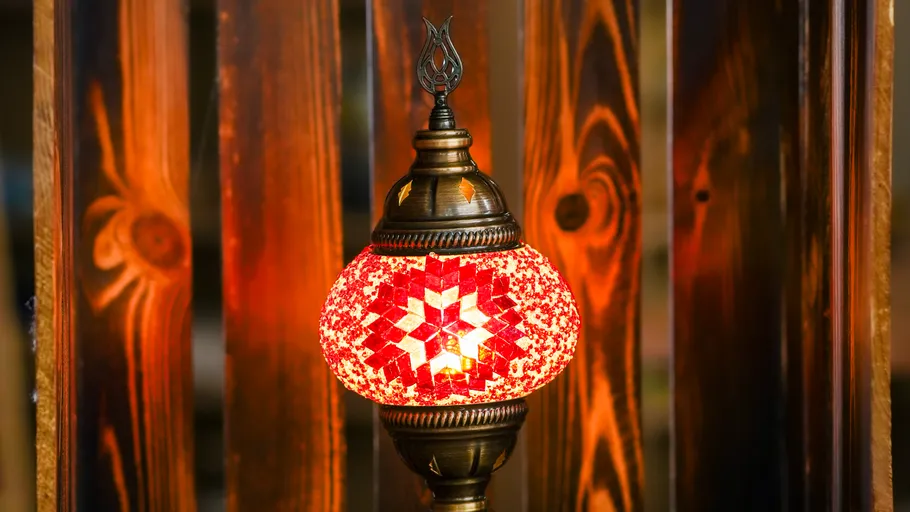 Decorative red lamp glowing, wooden background.