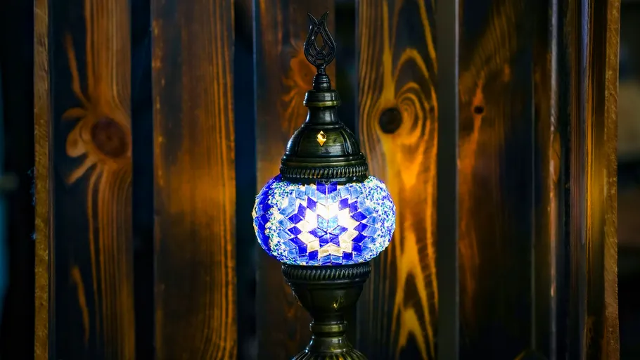 Decorative lamp glowing against wooden background.