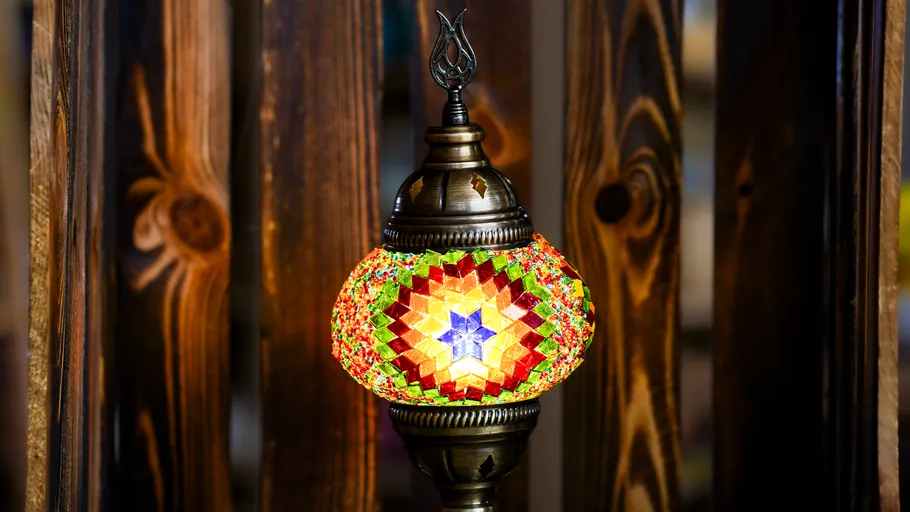 Bunte Mosaiklampe hängt in Holzumgebung.