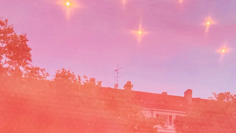 Sternenhimmel über Dächern und Bäumen.