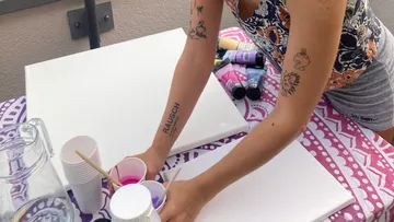 Person bereitet Farben auf einem Tisch vor.