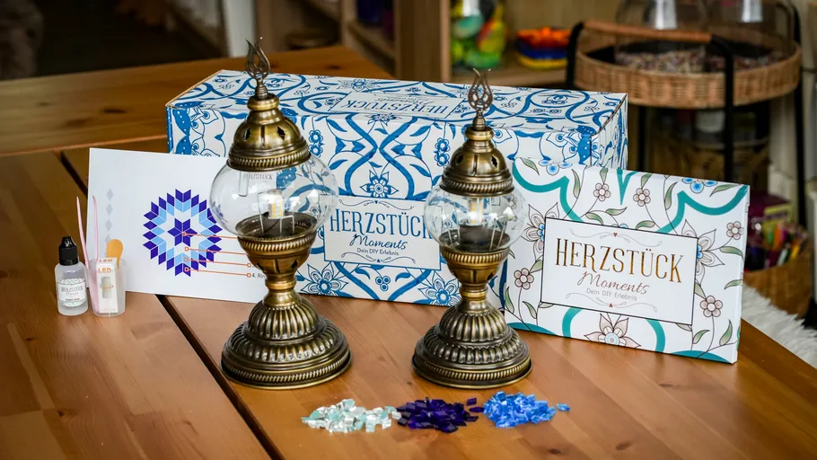 Two ornate lanterns with crafting supplies on table.