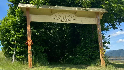 Holzbogen führt in einen Laubweg.