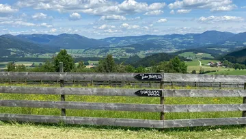 Bergblick mit Holzzaun im Vordergrund.