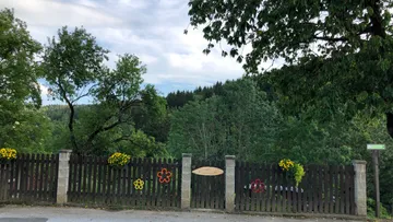 Wooden fence with colorful decorations, trees behind.