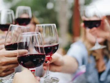 Gläser mit Rotwein werden zum Anstoßen erhoben.