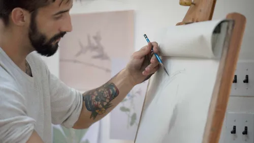Man drawing on easel in art studio.