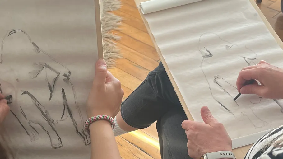 Two people drawing on sketchpads in a room.