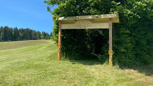Holzbogen auf Wiese nahe Wald.