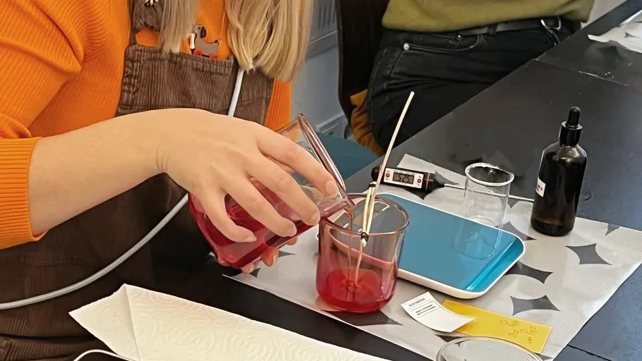 Person gießt rote Flüssigkeit in Becher.