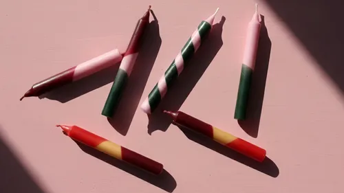 Bunte Kerzen auf rosa Fläche, werfen Schatten.