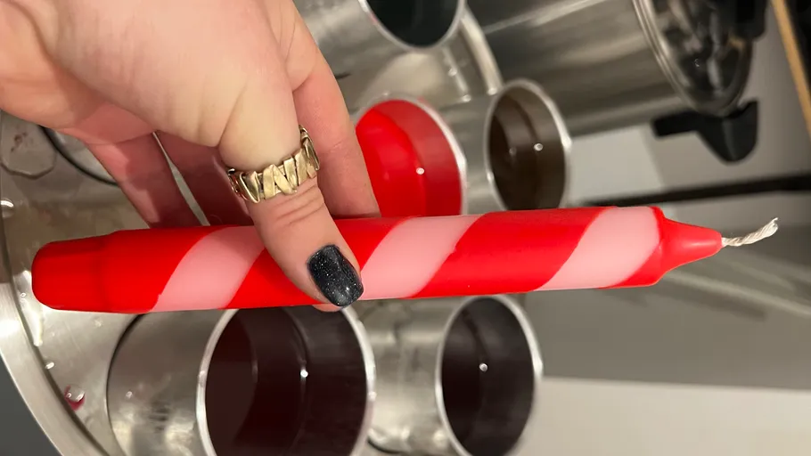 Hand holding red and white striped candle.