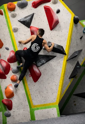 Man climbing indoor bouldering wall competitively.