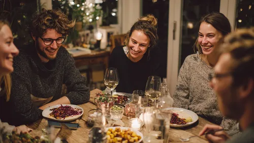 Group of friends laughing around dinner table.