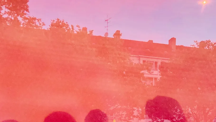 Silhouettes against pink smoke in a street.