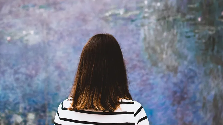 Woman in striped shirt viewing abstract art.