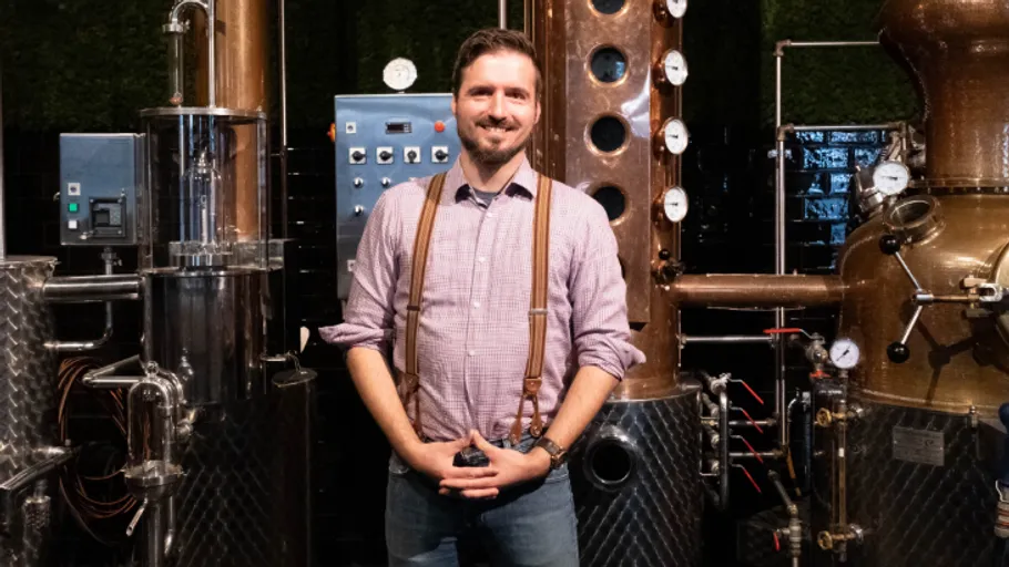 Man stands in distillery with machinery.