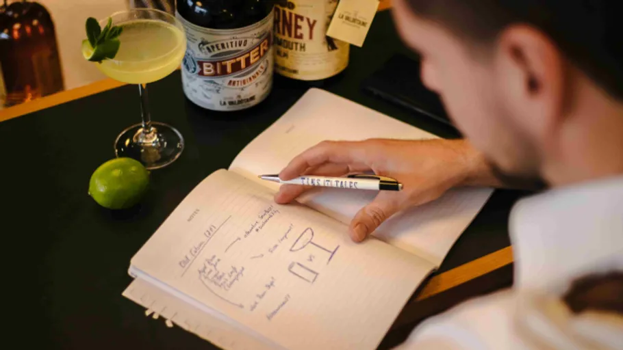 Person schreibt in Notizbuch an der Bar.