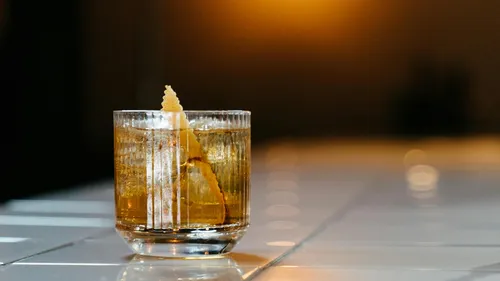 Glas Whisky mit Eis auf der Theke.