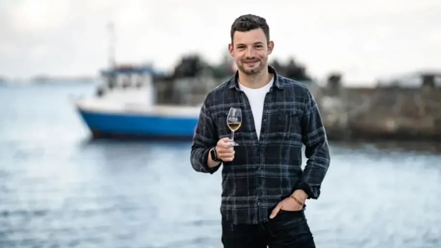 Man holding wine glass near a boat.