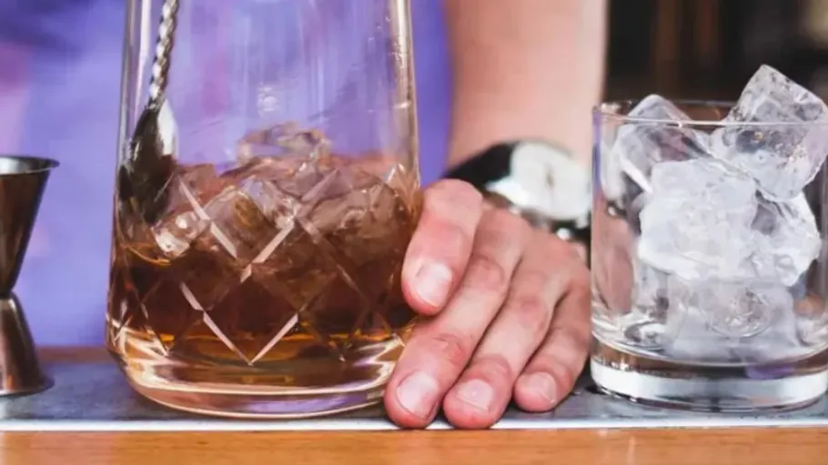 Person rührt Cocktail in einem Glas.