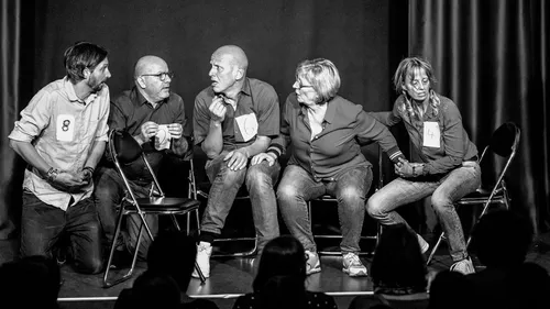 Five people performing on stage, seated on chairs.