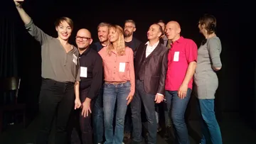 Group taking selfie on stage with smiles.